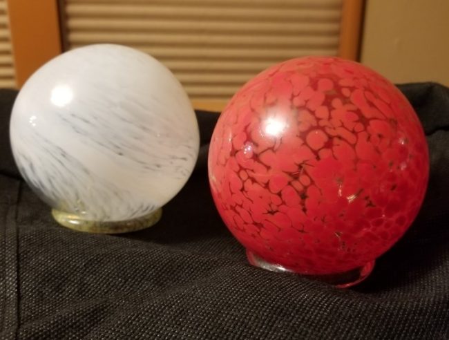 Two glass artwork globes, one white one red