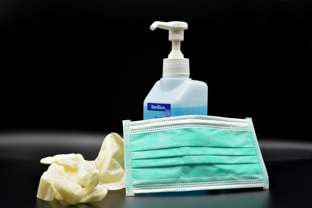 disposable glove, hand sanitizer, face mask on table with black background