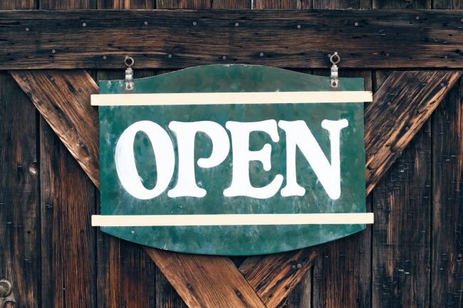 Green open sign on wooden gate