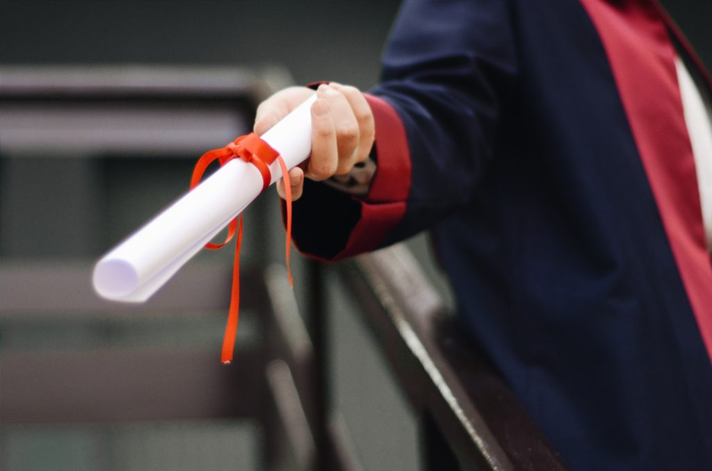 hand holding out a scroll with ribbon