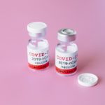 Vials of COVID-19 vaccine on pink background