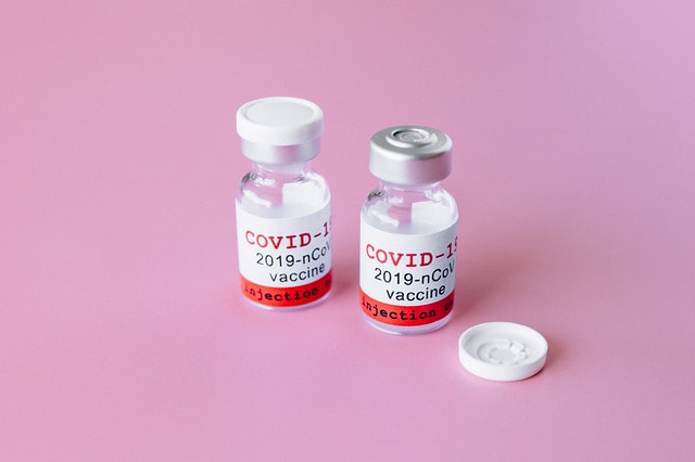 Vials of COVID-19 vaccine on pink background