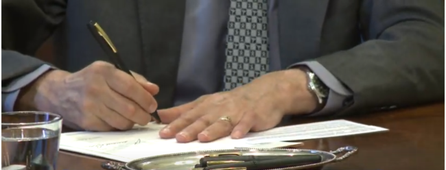 Close up photo of Gov's hand signing bills