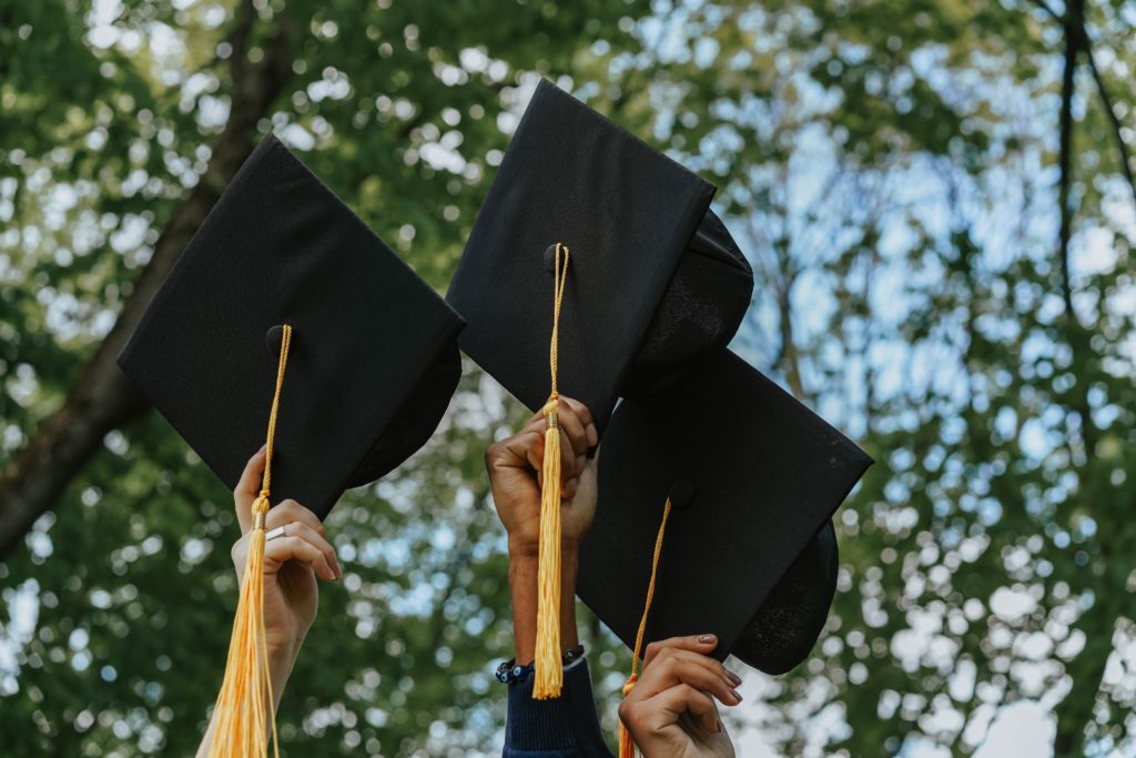 Mortarboards held up by hands