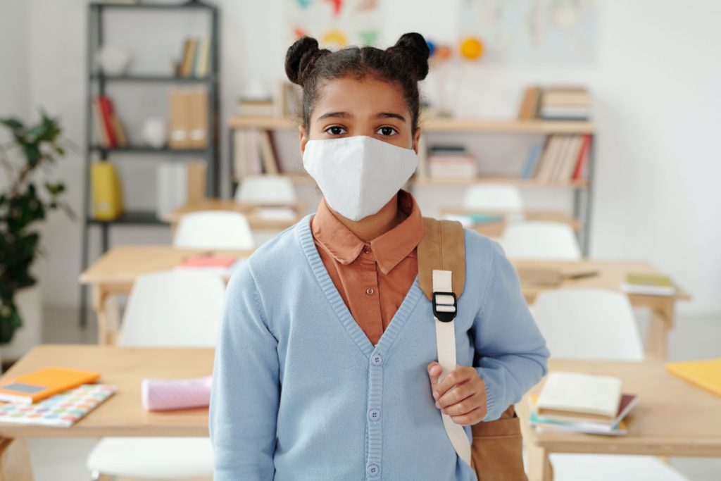 Student with mask and backpack in classroom