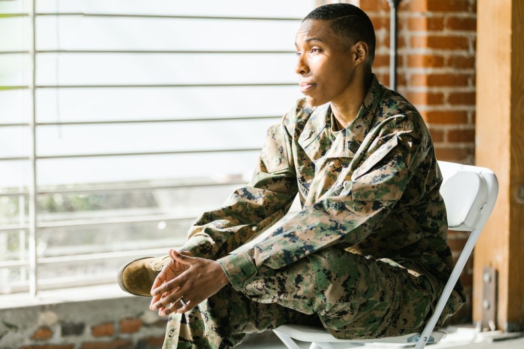 Woman in fatigues sitting in front of window