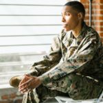 Woman in fatigues sitting in front of window