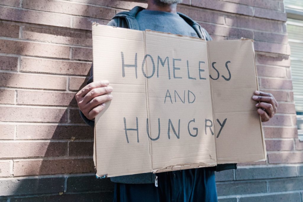Person holding sign saying "Homeless and Hungry"