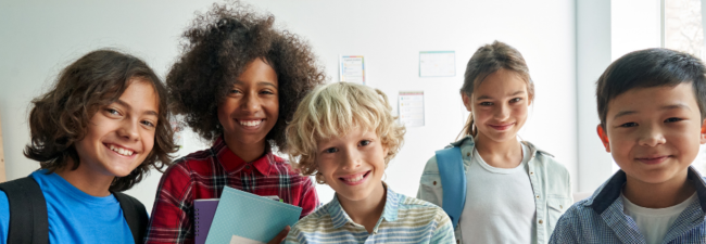 5 school kids of diverse backgrounds standing together in a row 