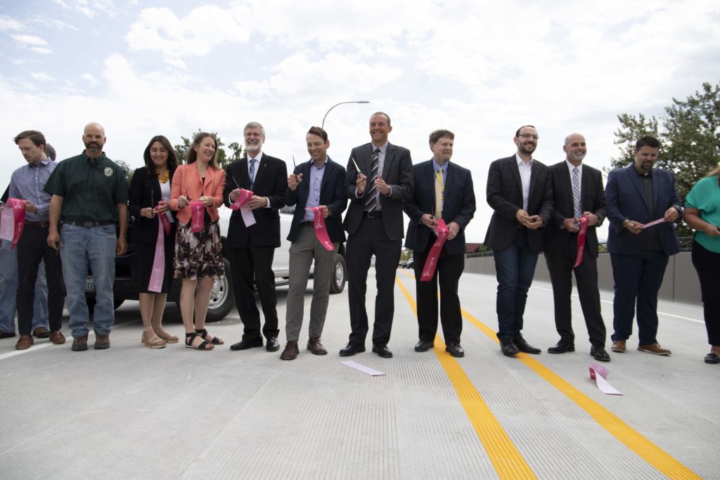 lawmakers and local officials including Representative Marcus Riccelli celebrating after cutting a pink ribbon to commemorate the opening of the East Trent Bridge replacement