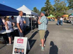 Rep. Marcus Riccelli standing in a farmer's market talking to a constituent.