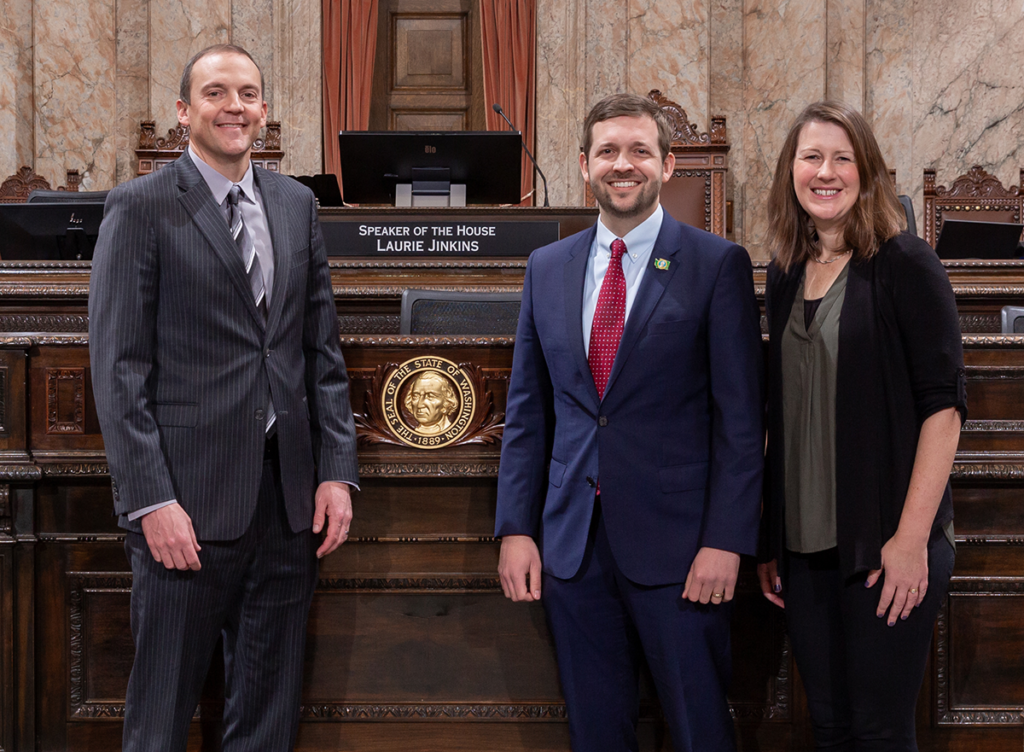 Rep. Riccelli standing with Spokane County commissioners Chris Jordan and Amber Waldref in front of the dais on the floor of the WA State House of Representatives.