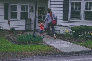 a woman with a boy walking toward the front door of their house