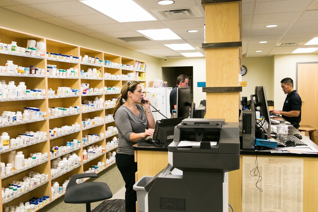 Photo of pharmacy workers taking calls and filling prescriptions