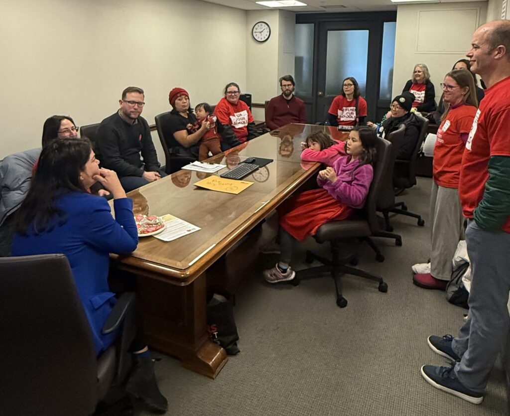 Rep. Berry speaking with parents, educators, and students from the Billion Dollar Bake Sale about school funding needs. They are sitting around a conference table.