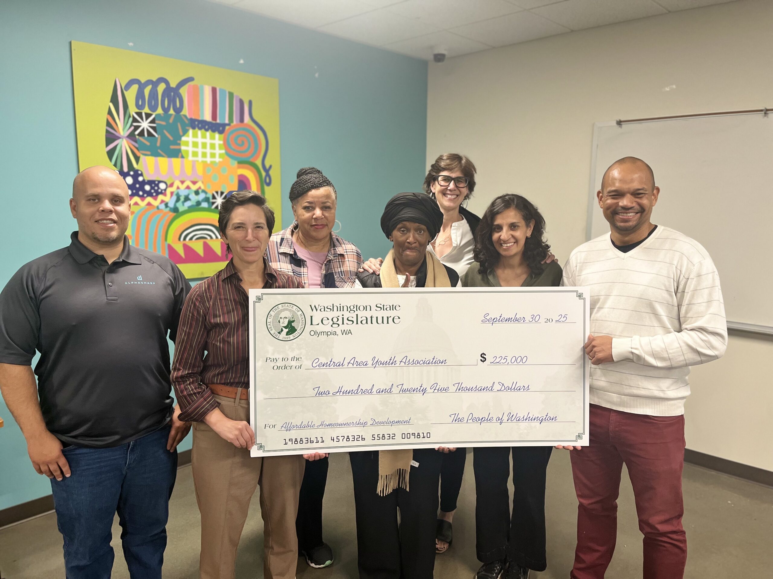 A group of people stand for a photo holding a large check for $225,000.
