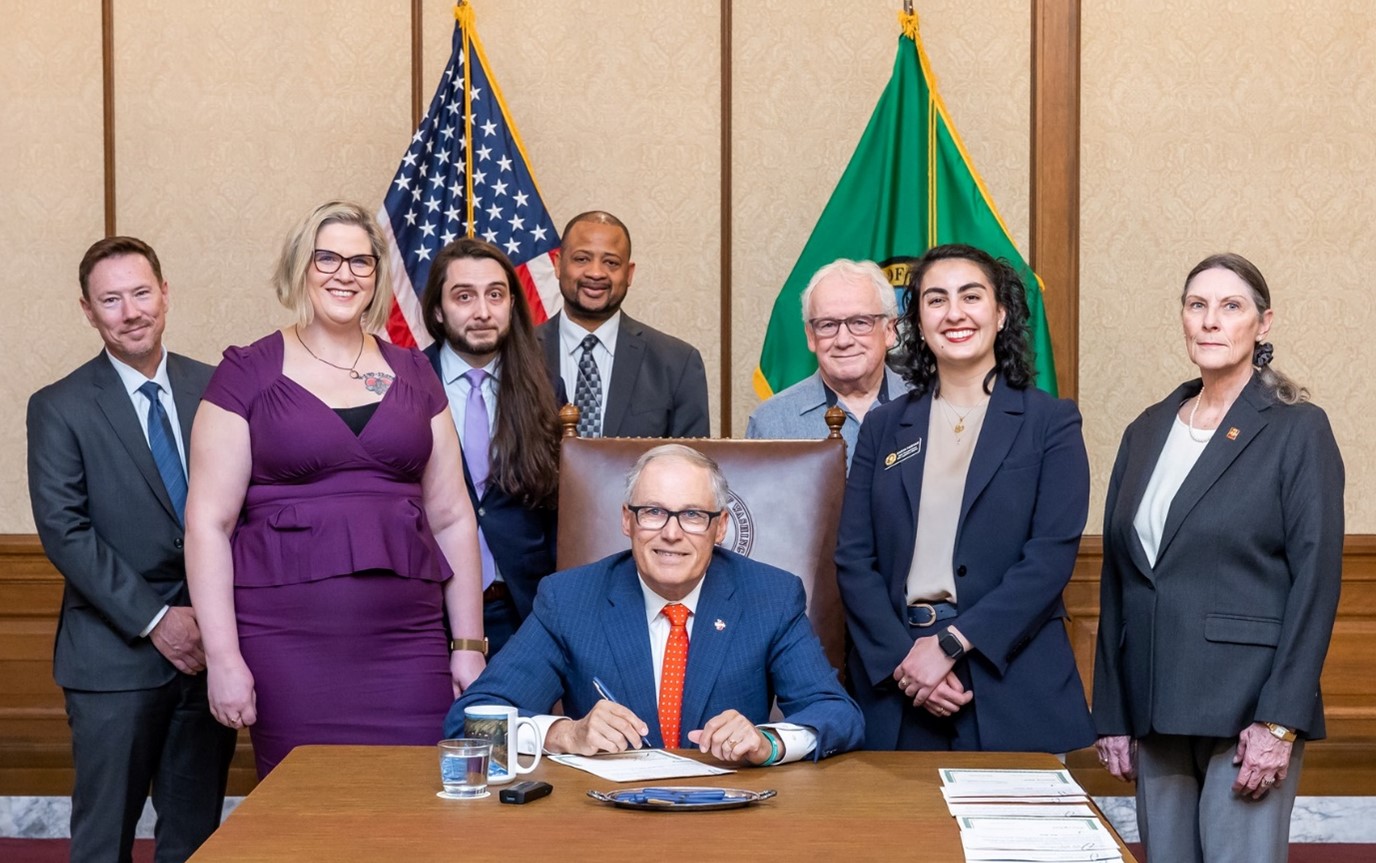 Rep. Farivar, staff, and stakeholders gather around Governor Inslee to sign House Bill 1345 into law